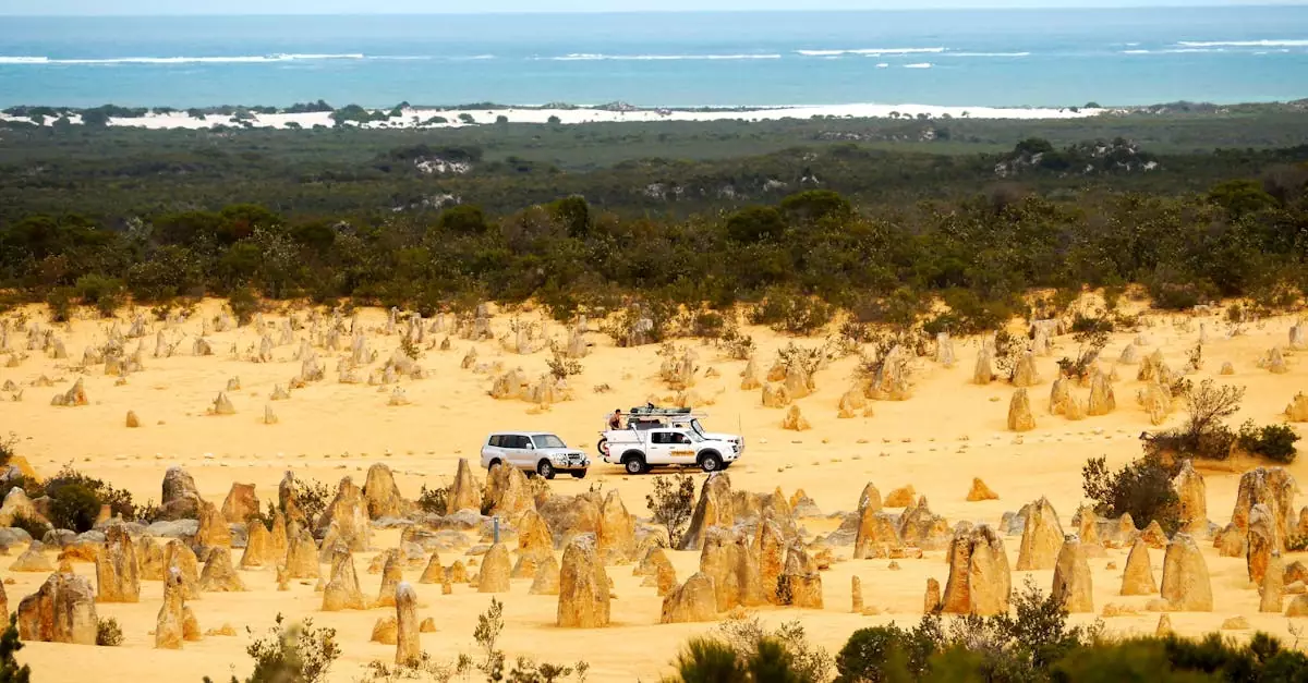 Scenic view of vehicles in the Pinnacles Desert, Western Australia, with ocean in the background.