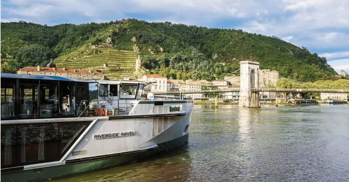 Elegant cruise ship travels along the scenic Rhone River near French vineyards and ancient architecture.