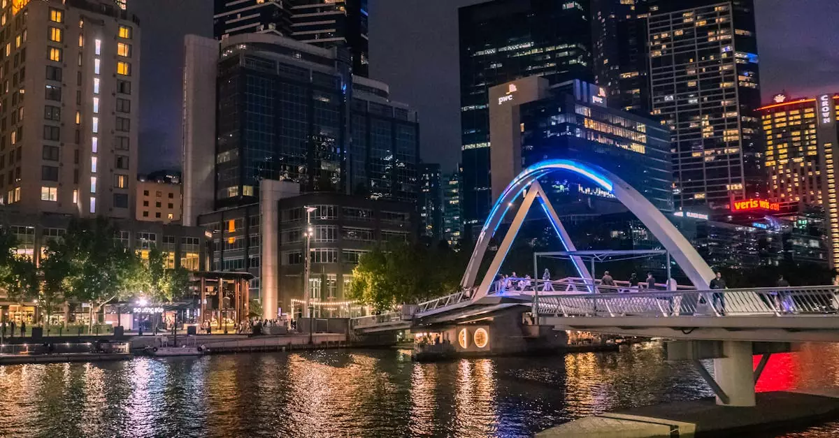 Illuminated Evan Walker Bridge crossing Yarra River in Melbourne's skyline at night.