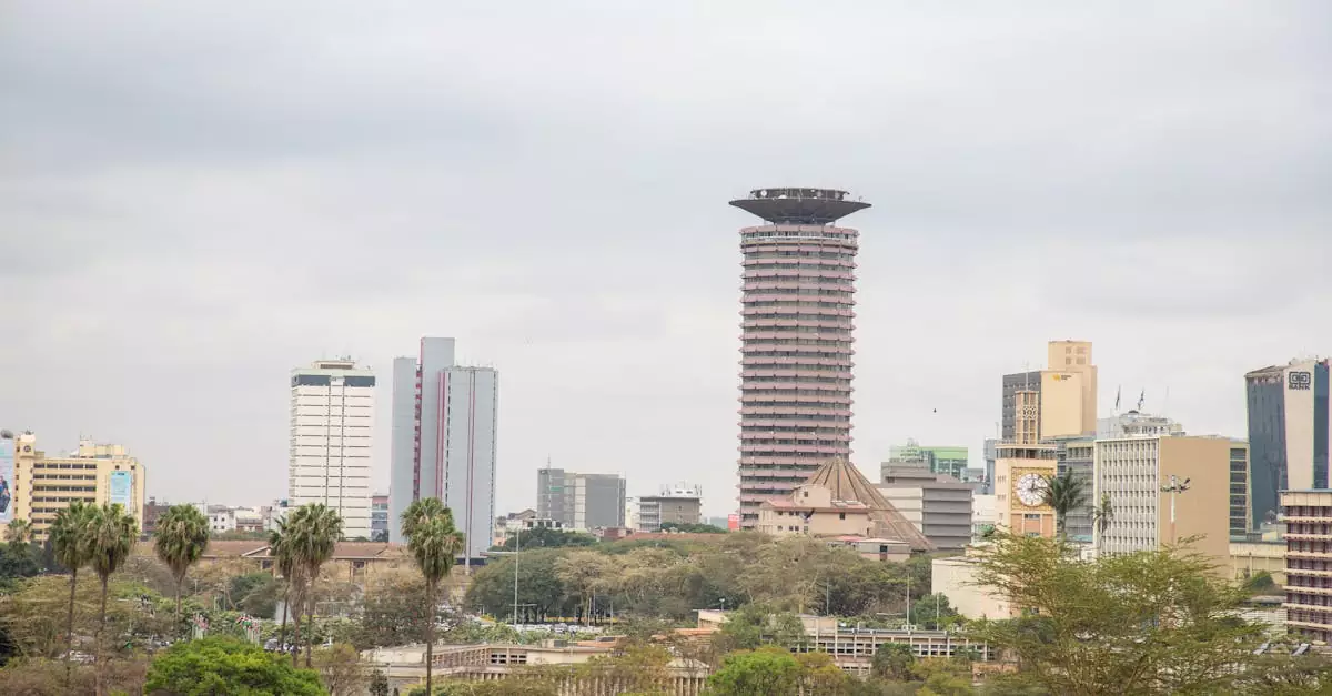 View of Nairobi's skyline with the iconic KICC tower and surrounding high rises under a cloudy sky.