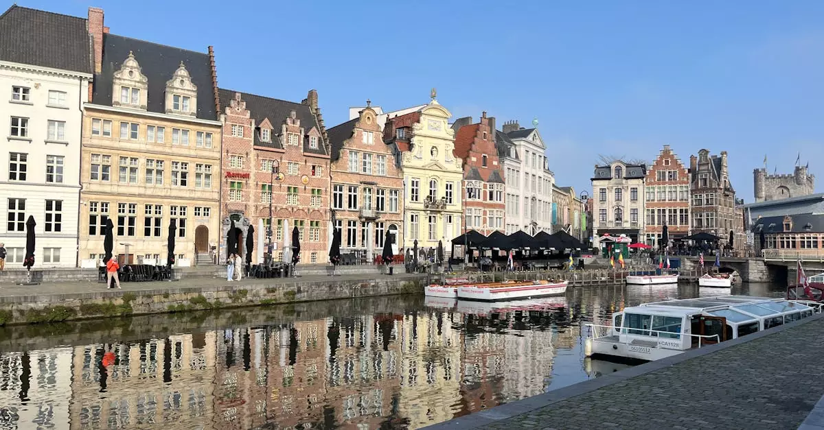 Scenic view of historic buildings and canal reflections along Graslei in Ghent, Belgium.