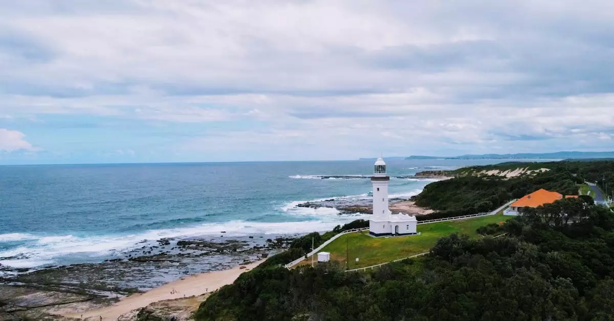 Aerial view of historic Norah Head Lighthouse by the Australian coast, surrounded by ocean and lush greenery.