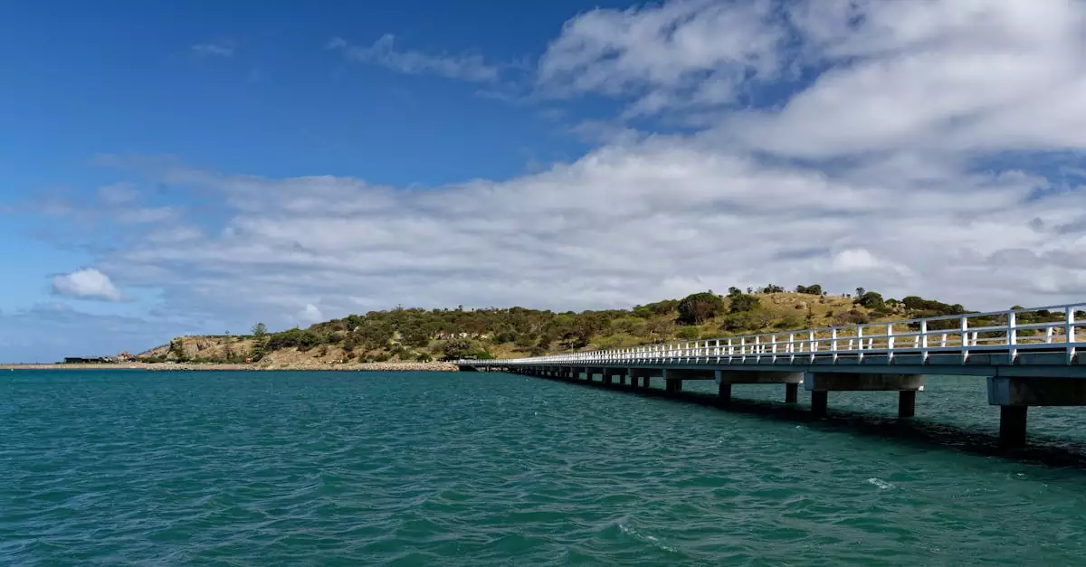 Long pier stretching into the sea with a scenic view of the coastline under a bright blue sky in Victor Harbor, Australia.