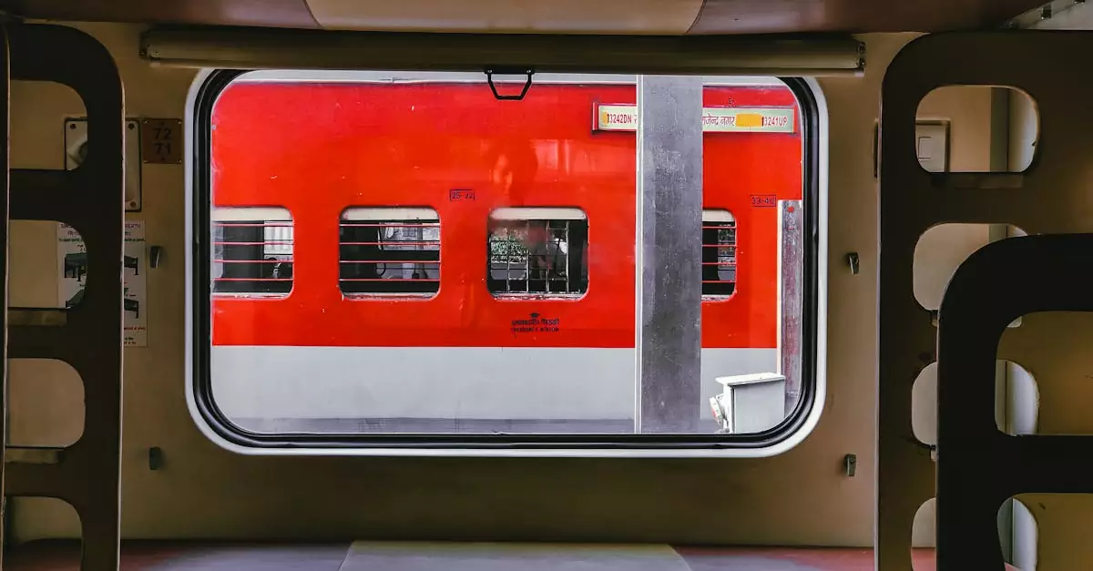 A vibrant red train viewed from another train window at a station, showcasing public transportation.