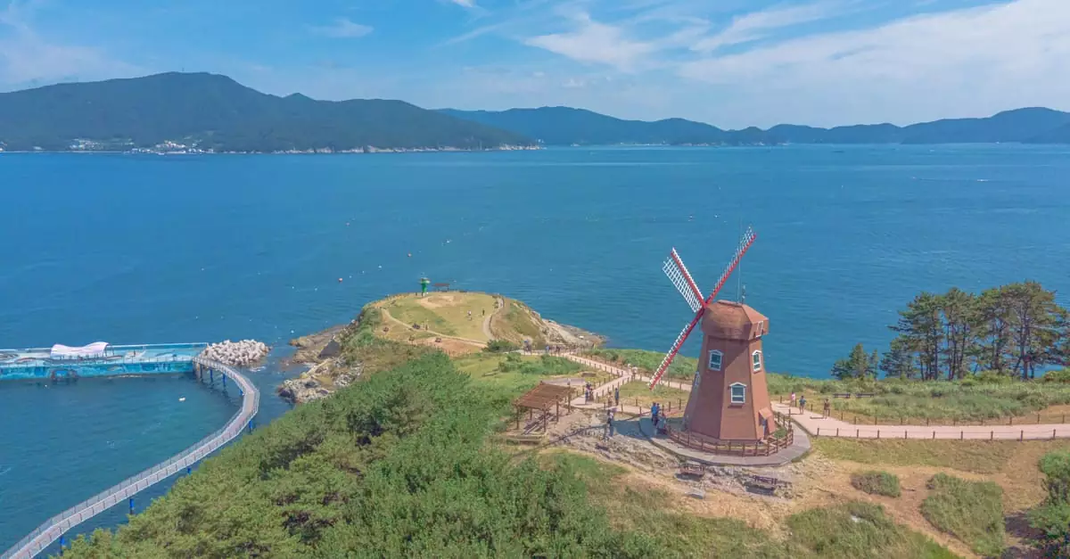 Aerial shot of Windy Hill's windmill overlooking the serene ocean in Geoje-si, South Korea.