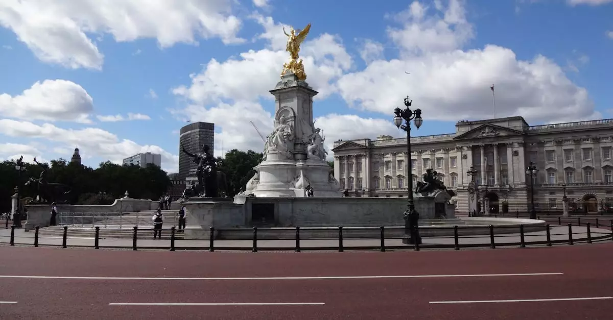 View of the Victoria Memorial with Buckingham Palace in the background under a bright blue sky.