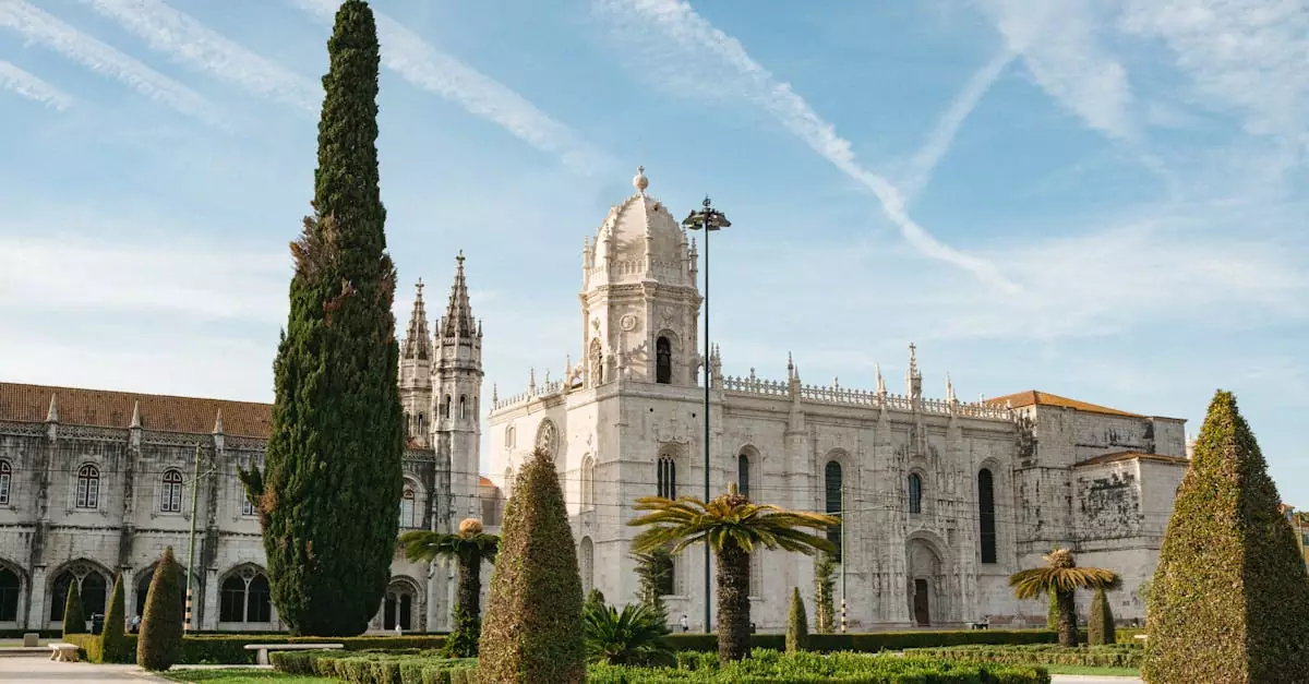 Stunning view of Jer&oacute;nimos Monastery's gothic architecture amidst lush gardens in Lisbon, Portugal.