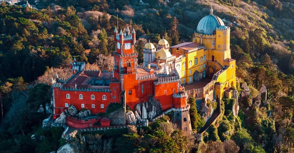 Breathtaking aerial shot of the colorful Pena Palace nestled in the lush hills of Sintra, Portugal.