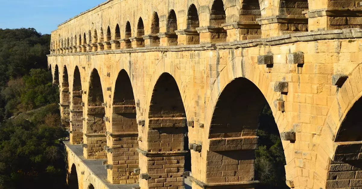 Elegant Roman aqueduct, Pont du Gard, basked in sunlight amidst lush scenery.
