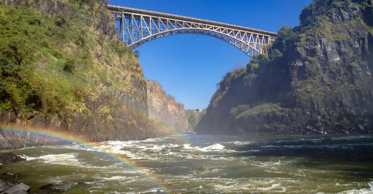 Stunning view of Victoria Falls Bridge surrounded by cliffs and a vibrant rainbow.
