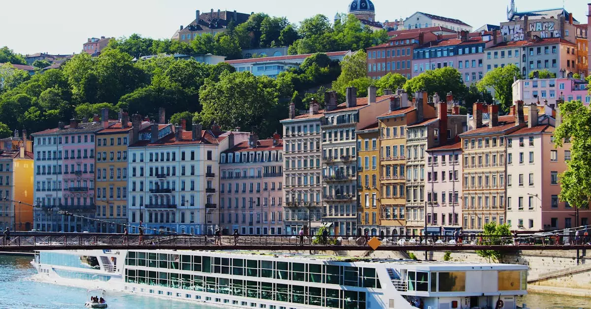 Colorful buildings along the riverbank in bustling Lyon, France, with a scenic cruise ship passing by.