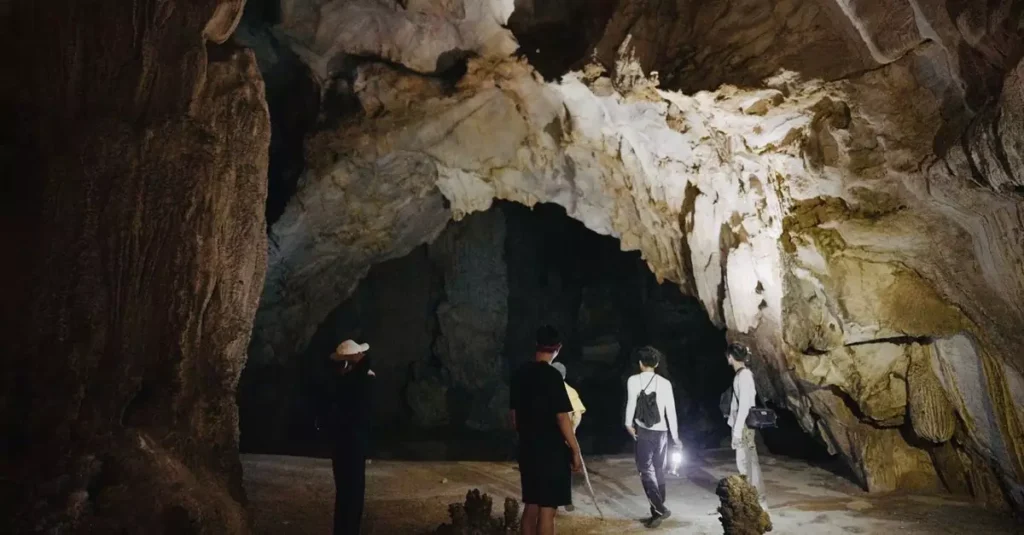 Actun Tunichil Muknal Cave Guide: Your Ultimate Adventure 2 Adventurers explore a vast, dimly lit cave with stunning rock formations.