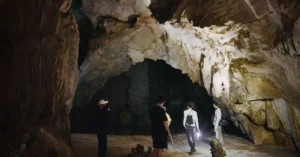 Adventurers explore a vast, dimly lit cave with stunning rock formations.