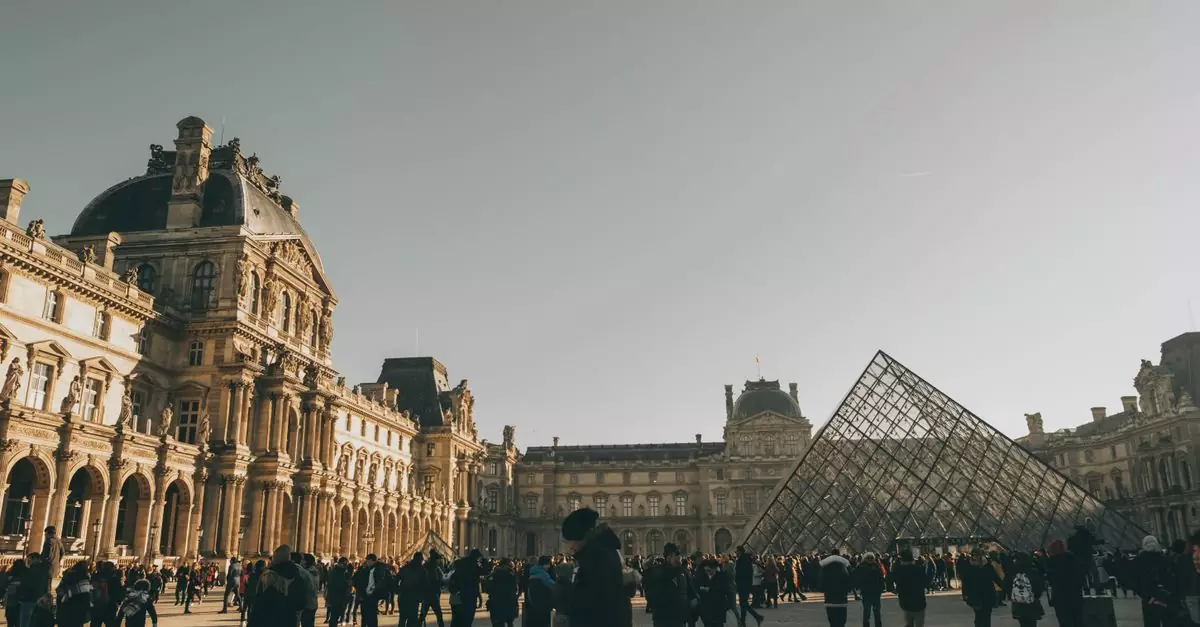 Tourists at the Louvre Museum with the iconic glass pyramid in Paris, France.