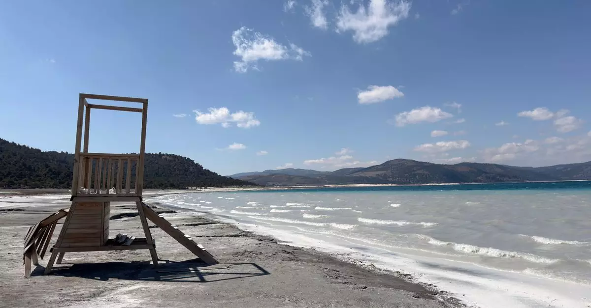 Peaceful scene of Salda Lake's clear waters and distinctive shores in Burdur, Türkiye under a bright sky.