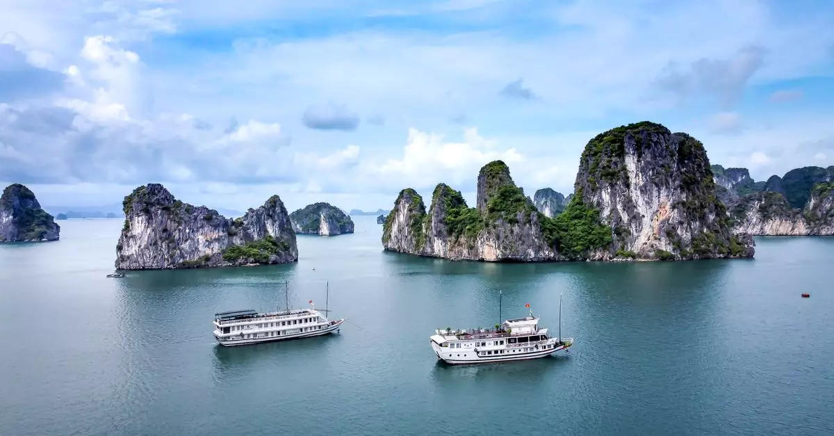 Seascape of majestic cliffs with greenery in tranquil turquoise sea and ships under cloudy blue sky