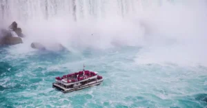 From above of yacht with anonymous tourist sailing on rippled river near rapid splattering cascade