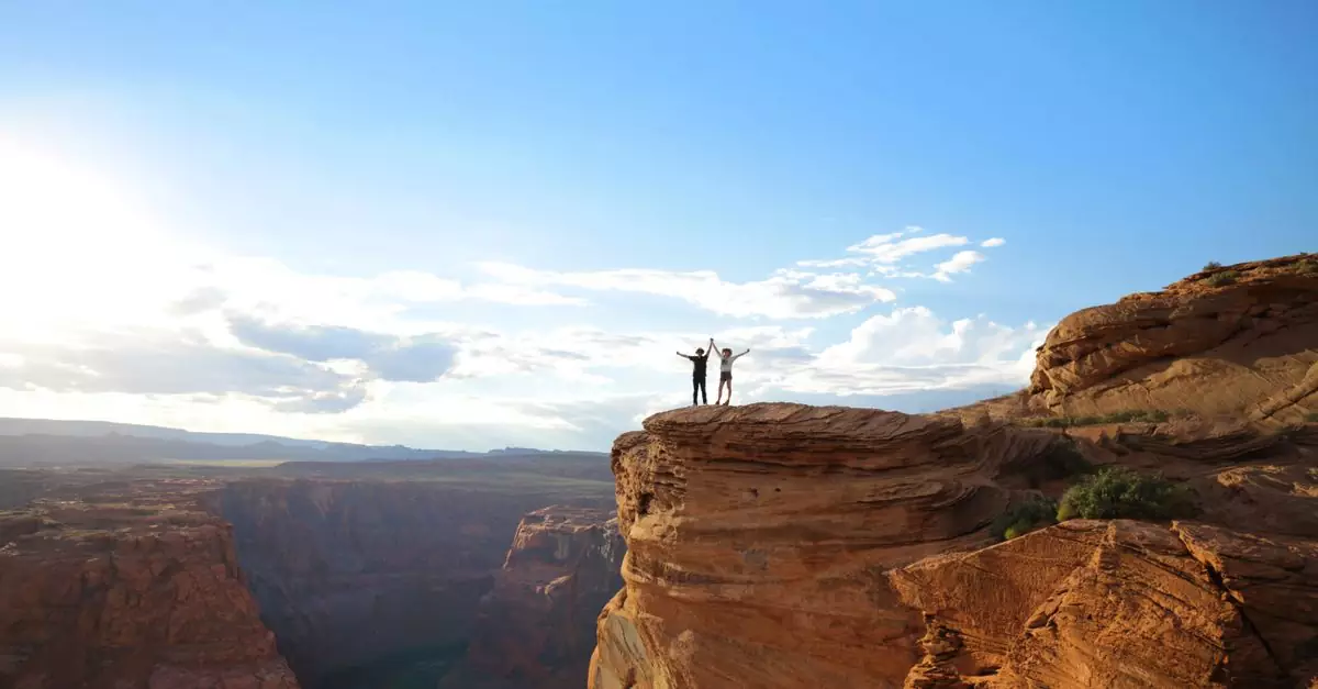 Two adventurers stand triumphantly on Horseshoe Bend cliff under a bright, blue sky.