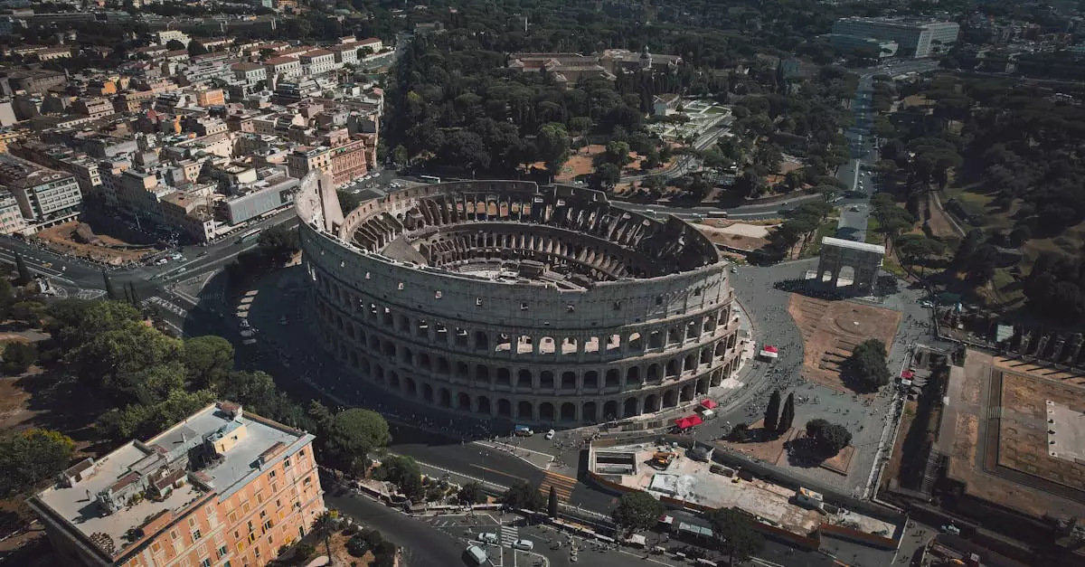 High angle drone shot of the Colosseum in Rome, Italy, showcasing its grandeur and surrounding urban landscape.