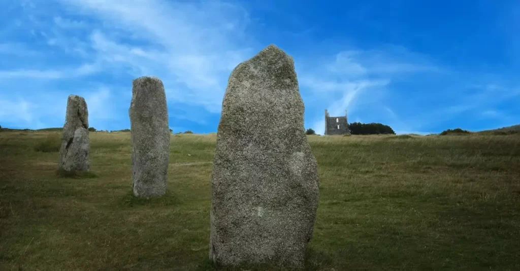 Best Ancient Mysteries in Europe: A Time Travel Guide 2 Explore the mystical stone circle in Minions, UK with a historic building in the background.