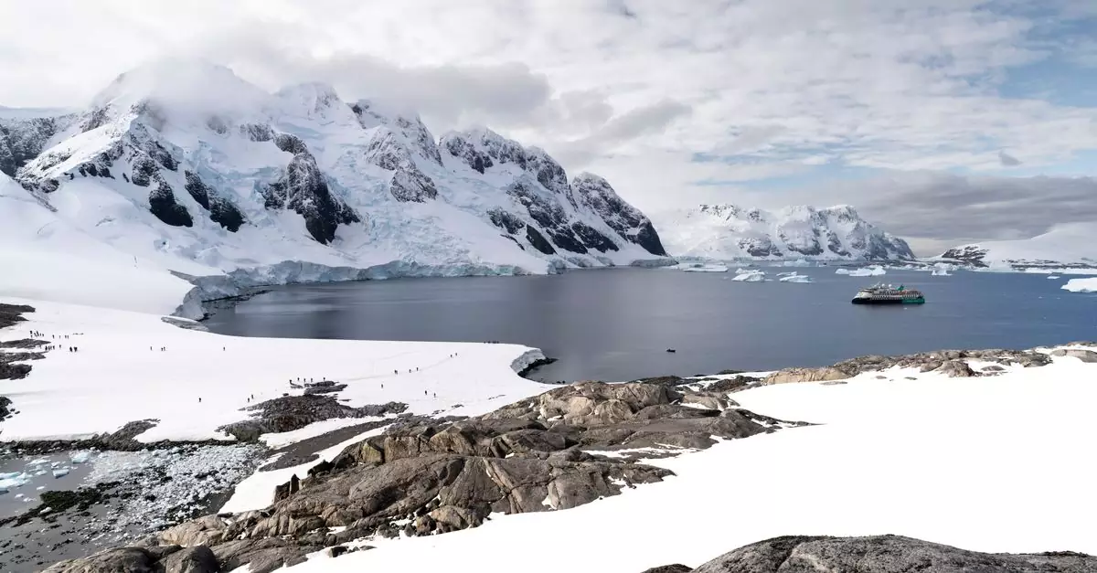 Scenic Antarctic view with icy mountains, calm waters, and a solitary boat.