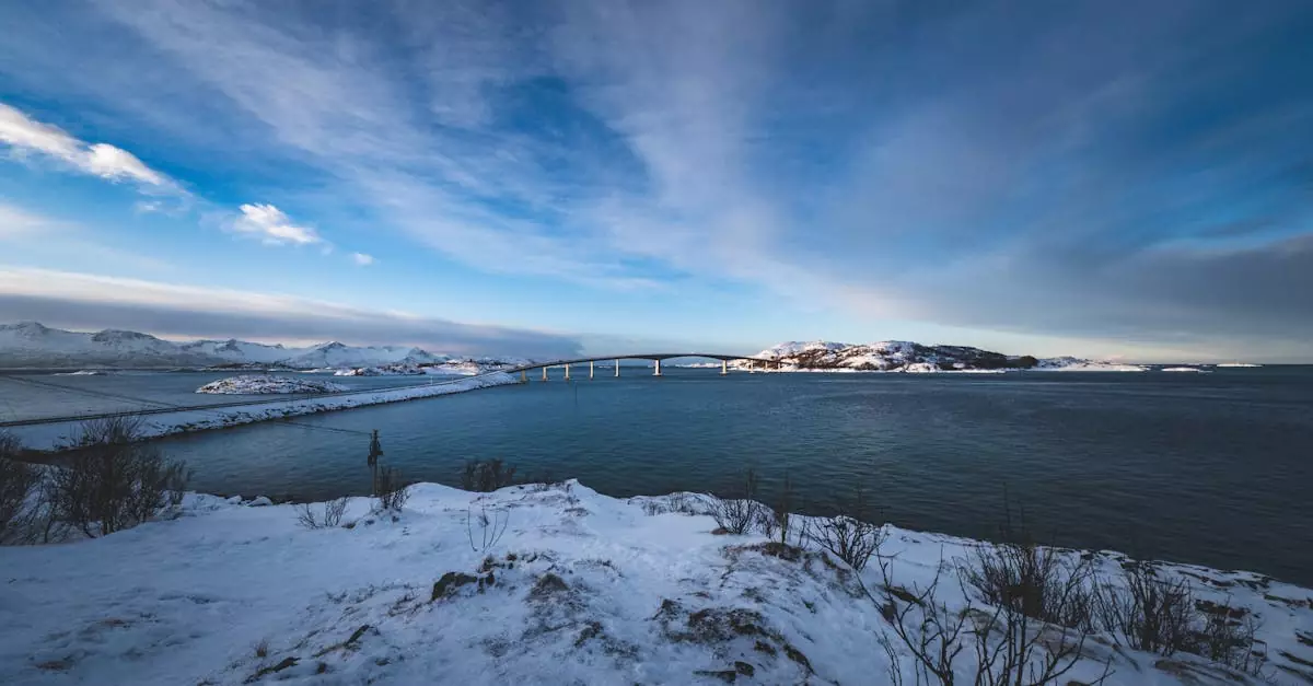 A picturesque winter view of the Atlantic Ocean Road bridge surrounded by snowy landscapes in Norway.