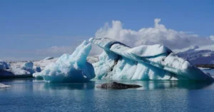 Crystal blue icebergs floating in Jokulsarlon Glacier Lagoon, Iceland, under a clear sky.