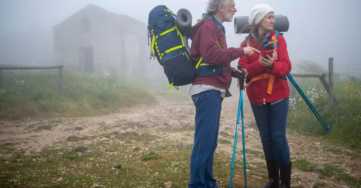 Elderly couple hiking with backpacks and trekking poles in a misty landscape in Portugal.