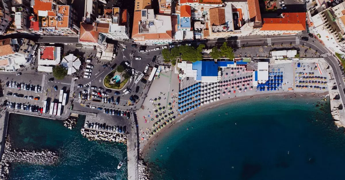 Stunning aerial view of Amalfi's beach, colorful umbrellas, and historic town buildings.