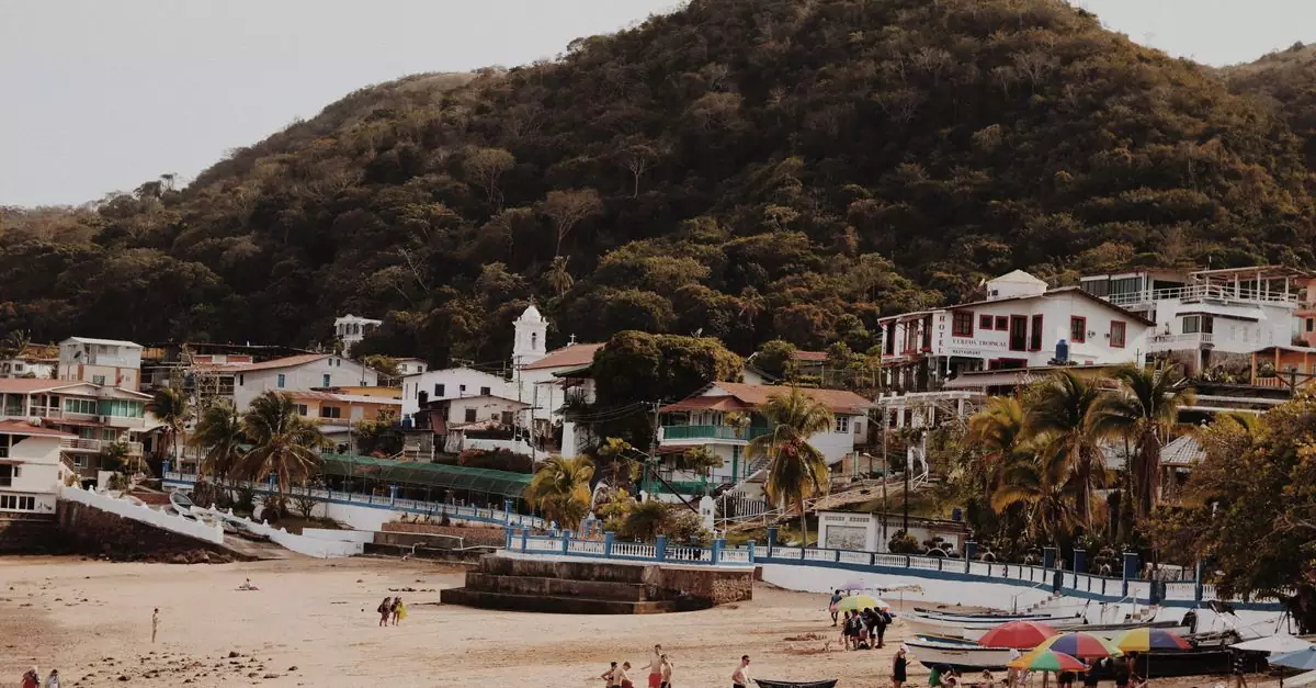 Discover a vibrant beach town nestled against lush hills, perfect for summer vacations.