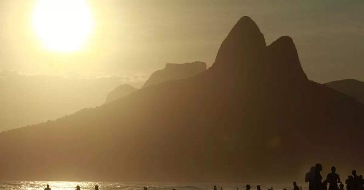 Silhouetted beachgoers enjoy a scenic sunset at Ipanema Beach with Two Brothers Mountain in view.