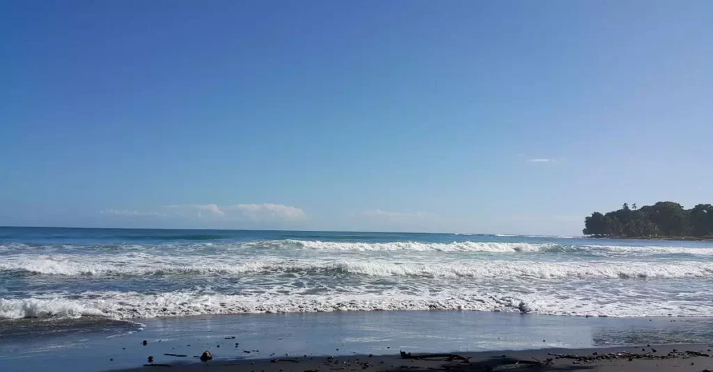 Best Beaches Central America: Pacific to Caribbean Guide 2 Serene view of a sunny beach in Puerto Viejo, Costa Rica with gentle waves and clear skies.