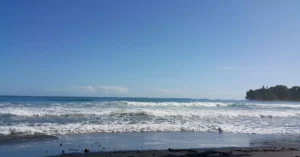 Serene view of a sunny beach in Puerto Viejo, Costa Rica with gentle waves and clear skies.