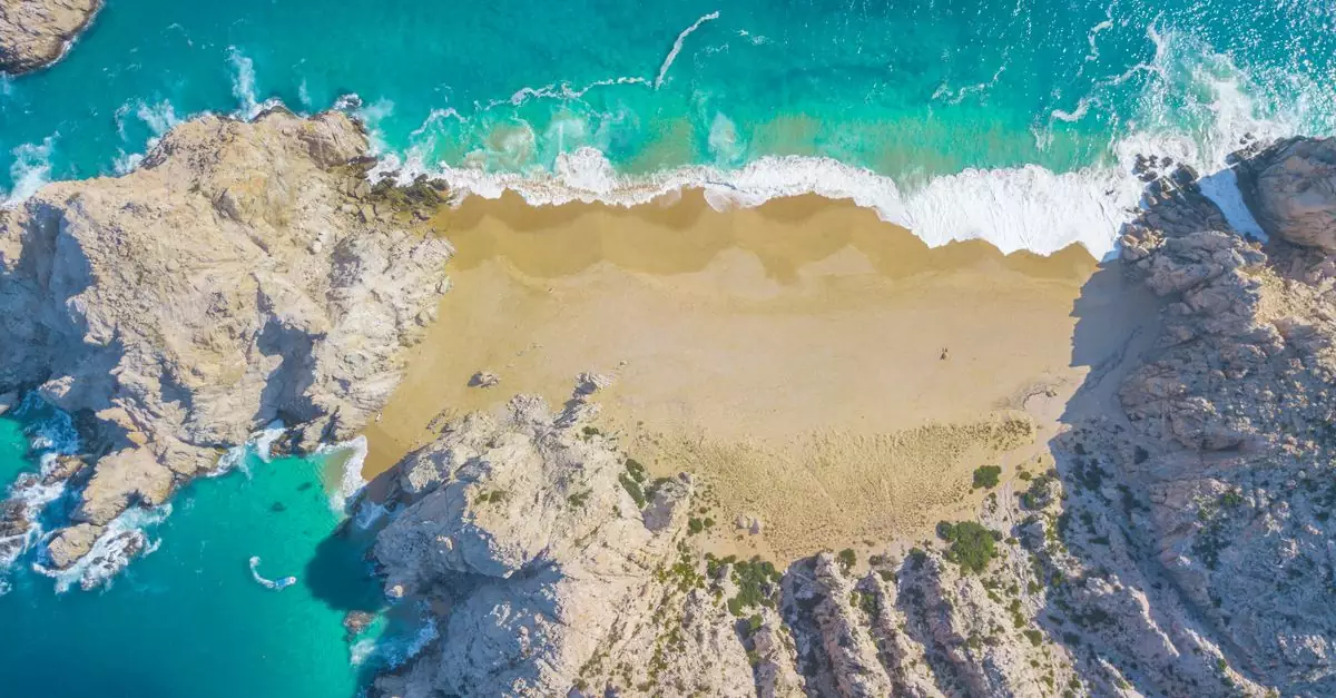 A stunning aerial view of Divorce Beach in Cabo San Lucas, showcasing turquoise waters and golden sands.