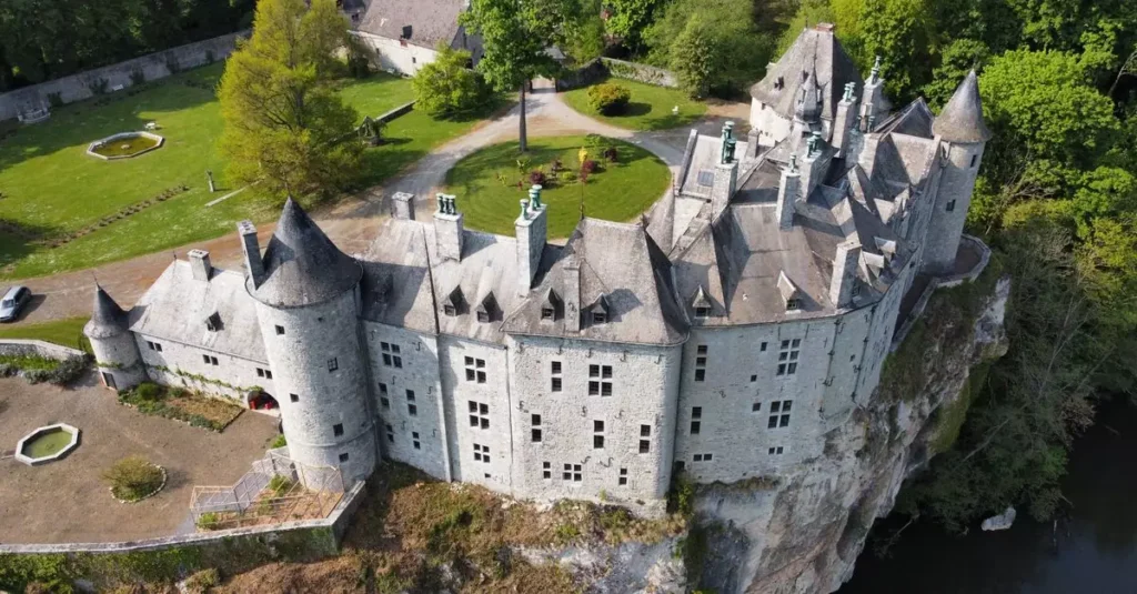 Best Belgium History Destinations: Bruges, Ghent & More 2 Stunning aerial shot of historic castle in Dinant, Belgium, surrounded by greenery.