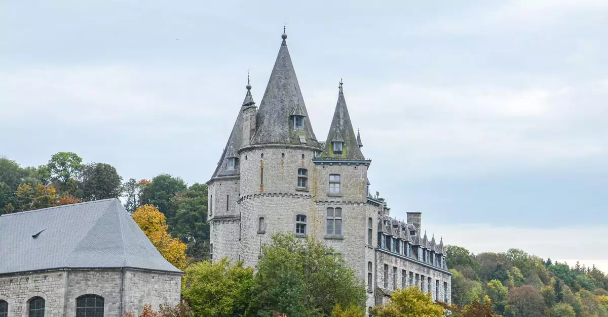 Explore the enchanting medieval castle in Durbuy, Belgium, surrounded by vibrant autumn foliage.