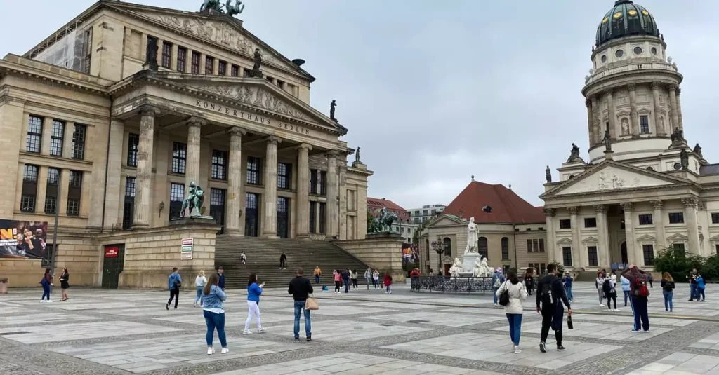 Best Berlin Day Trips: Palaces, Nature & Towns 2 Tourists explore Gendarmenmarkt Square in Berlin with the Concert Hall and French Cathedral.