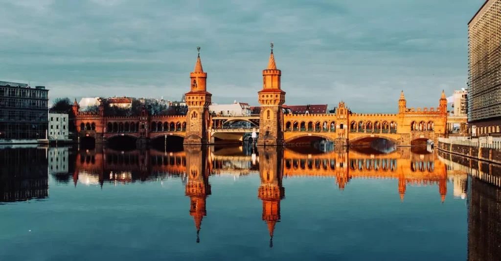 Best Berlin Neighborhoods for Every Traveler 2 Stunning view of Berlin's Oberbaum Bridge reflecting in the Spree River during a picturesque sunset.