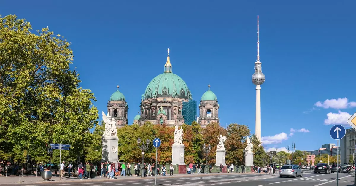 Iconic view of Berlin Cathedral and TV Tower surrounded by city life and clear blue skies.