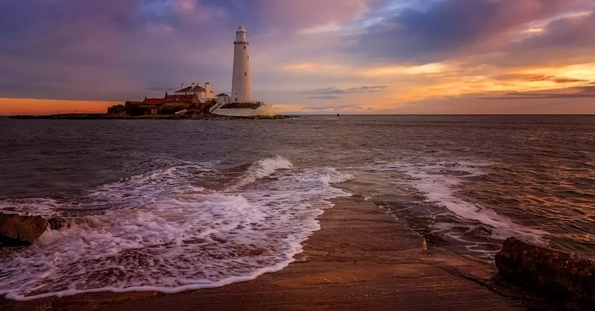 A stunning view of St Mary's Lighthouse at sunset with dramatic skies and ocean waves.