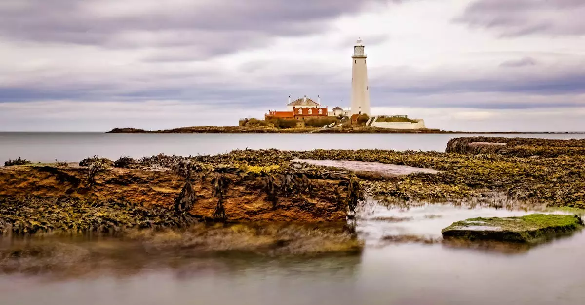 Scenic view of St Mary's Lighthouse in Whitley Bay with rocky foreground and cloudy sky.