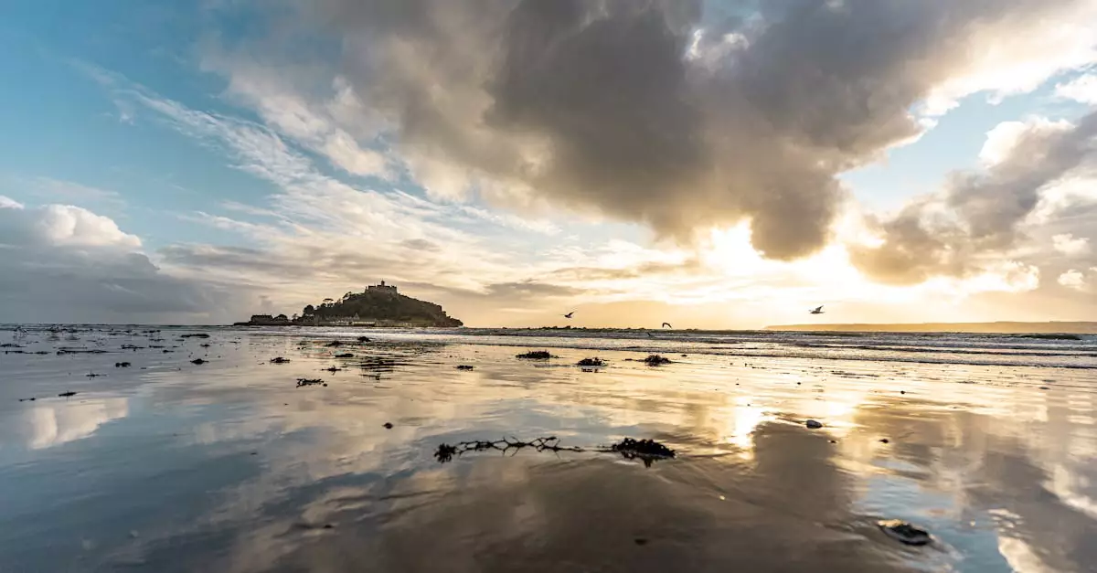 Capture of Saint Michael's Mount at sunset with dramatic clouds reflecting on the water in Cornwall, UK.