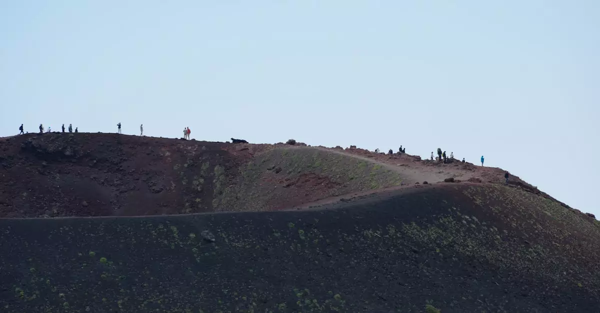Hikers exploring the rugged landscape of Mount Etna, Sicily, under a clear sky.
