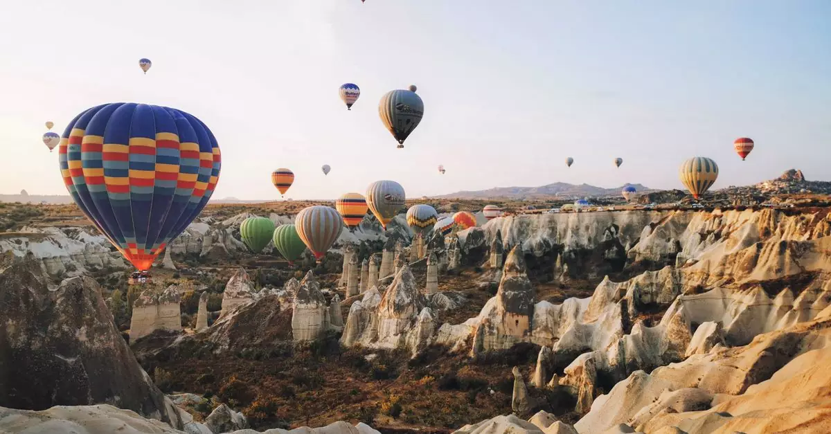 Colorful hot air balloons floating over Cappadocia's unique rock formations at sunrise.