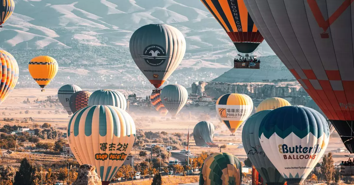 Stunning view of colorful hot air balloons flying over Cappadocia's unique landscapes in Türkiye.