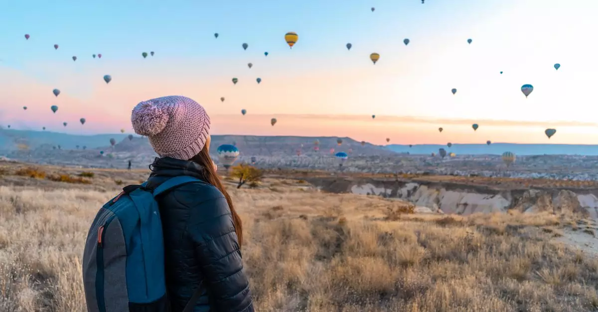 Woman watching hot air balloons in Cappadocia at sunrise, a popular travel destination.