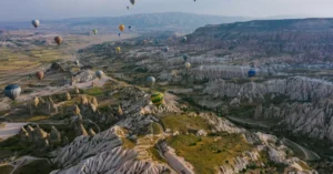 A breathtaking aerial view of hot air balloons floating over Cappadocia's scenic rock formations.