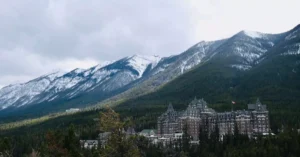 Scenic view of Banff Springs Hotel amidst snow-capped mountains and greenery.