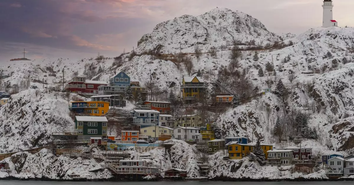 Winter cityscape of St. John's, NL, with colorful houses and a lighthouse, blanketed in snow.