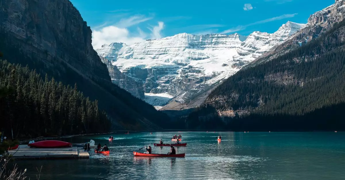 Serene view of canoes on Lake Louise surrounded by snow-capped mountains in Banff National Park, Alberta.